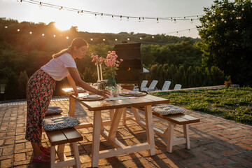 Attractive woman setting a table for the dinner in the backyard