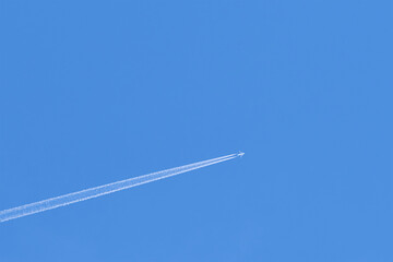 Plane trail on clear blue sky. Copyspace.