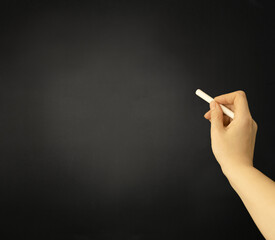 Chalk board. Hand with white chalk on the background of a graphite chalk board.