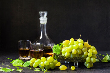 Fresh ripe grapes and decanter with grape juice on black background