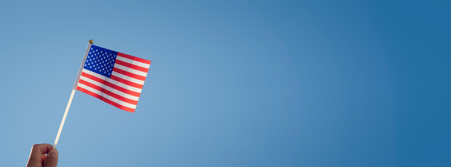 Waving an American flag over blue sky background