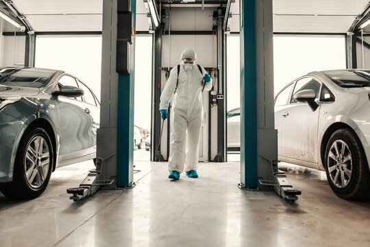 A Male Professional In A Protective Suit Prevents The Spread Of The Infection In The Car Garage. Coronavirus Defense, Stay Healthy, Warning For COVID 19, Snitation, Deep Cleaning, Pandemic Situation