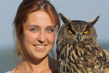 Happy woman holding royal owl looking at camera