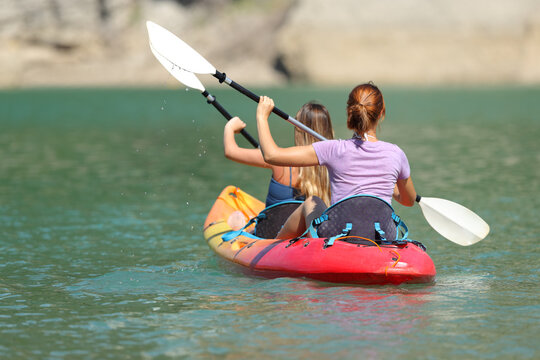 Two Women Rowing In A Tandem Kayak In A Lake