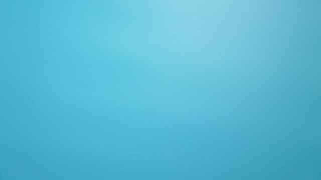 Close-up 4k video footage of female caucasian hand isolated on blue background. Young adult woman forming shape of half of heart with her fingers. Point of view shot with copy space