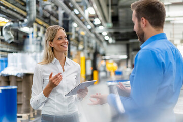 Smiling businesswoman having discussion with coworker at industry