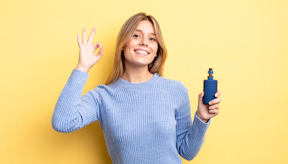 pretty blonde girl feeling happy, showing approval with okay gesture. smoke vaporizer concept
