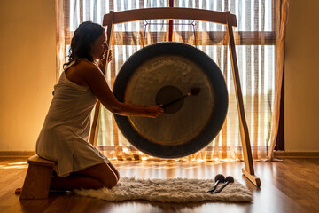 Sound healerl playing gong while sitting by window