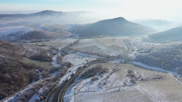 Aerial view of a winding road with driving cars in a frosty winter sunny day by drone