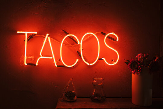 Glowing red sign with tacos written on the wall