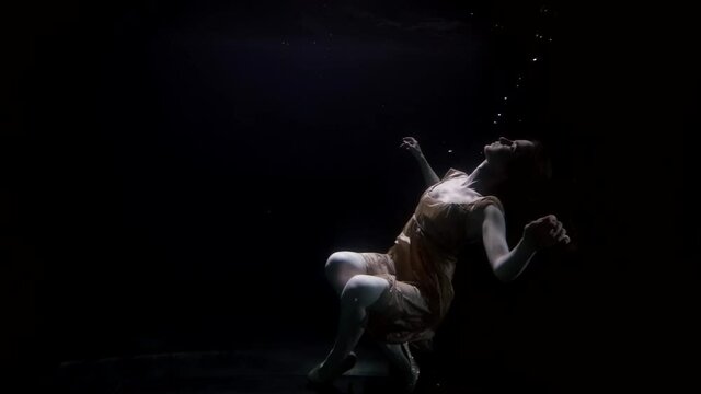 woman is plunging in deepness, underwater shot, female figure in darkness