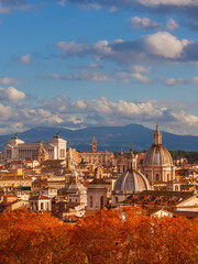 Fototapeta premium Autumn in Rome. View of the historical center skyline just before sunset with old monuments, baroque domes and red leaves