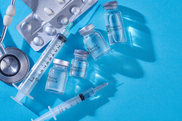 medical tool syringe and vaccine bottle on blue background