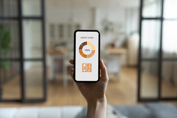 Close up back view of woman hold modern cellphone use smart home application on gadget screen....