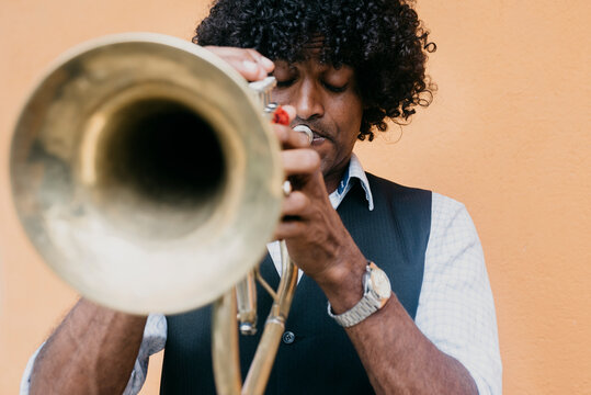 Man playing trumpet in front of beige wall