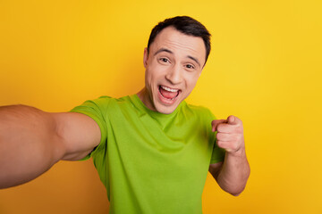 Portrait of crazy excited guy make selfie show okey symbol direct finger you open mouth on yellow background