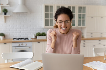 Overjoyed millennial Caucasian female look at laptop screen feel euphoric with online win or victory. Happy smiling young woman triumph read good hiring or promotion news on computer. Luck concept.
