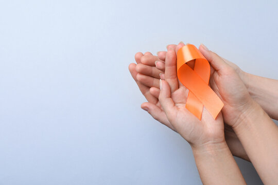 Couple holding orange ribbon on light grey background, top view with space for text. Multiple sclerosis awareness - Powered by Adobe