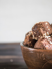Brown.vegetarian sweets close-up, garnished with sesame seeds and carob powder in a ceramic bowl on a wooden table. Energy balls.  Raw food sweets. Proper nutrition.