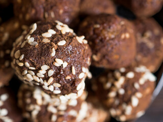 Close-up brown.vegetarian sweets garnished with sesame seeds and carob powder. Energy balls.  Raw food sweets. Proper nutrition.