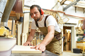 carpenter works in a joinery - workshop for woodworking and sawing