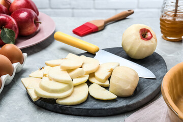 Cut fresh apple with knife and board on grey table. Baking pie