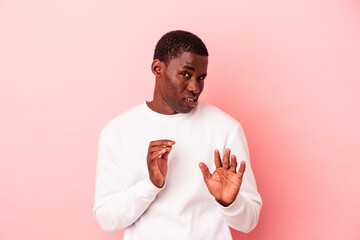 Young African American man isolated on pink background rejecting someone showing a gesture of...