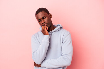 Young African American man isolated on pink background looking sideways with doubtful and skeptical expression.