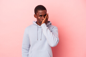 Young African American man isolated on pink background who feels sad and pensive, looking at copy space.