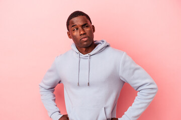 Young African American man isolated on pink background frowning face in displeasure, keeps arms...