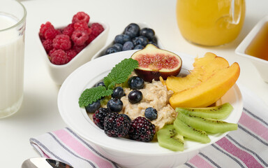full plate with oatmeal and fruit, freshly squeezed juice in a transparent glass decanter. Healthy breakfast