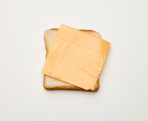 Fototapeta na wymiar square slices of toasted bread made from white wheat flour and a slice of cheddar cheese on top. White table background