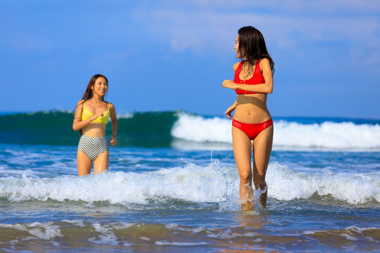 Young women running in water during vacation