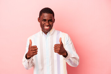 Young African American man isolated on pink background smiling and raising thumb up