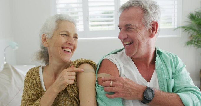 Animation of happy caucasian senior couple showing plasters after vaccination