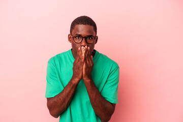 Young African American man isolated on pink background shocked covering mouth with hands.