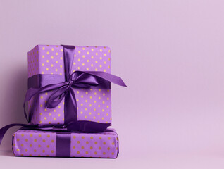 boxes packed in festive purple paper and tied with silk ribbon on a purple background, birthday...