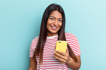 Young Venezuelan woman holding mobile phone isolated on blue background happy, smiling and cheerful.