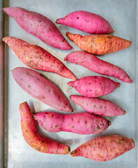 Raw Japanese sweet potatoes on an aluminum tray ready to be baked in the oven.