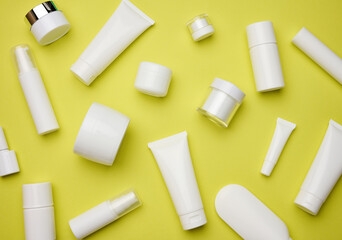 jar, bottle and empty white plastic tubes for cosmetics on a yellow background. Packaging for...