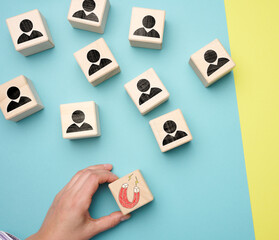 female hand holds a wooden cube with a magnet and wooden cubes with little men, recruiting for a strong team. Open vacancies in the company