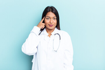 Young doctor Venezuelan woman isolated on blue background pointing temple with finger, thinking, focused on a task.