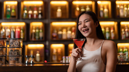 Nightlife concept in the night club a pretty woman with a pink drink in her hand looking very happy perhaps due to the atmosphere