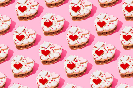 Pattern of heart shaped cookie cakes flat laid against pink background