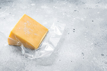 Organic Sharp Cheddar Cheese in vacuum packaging. Gray background. Top view. Copy space