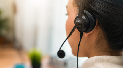 Back view of woman consultant wearing microphone headset of customer support phone operator at...