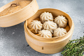 Steamed baozi dumplings stuffed with meat in a bamboo steamer. Gray background. Top view
