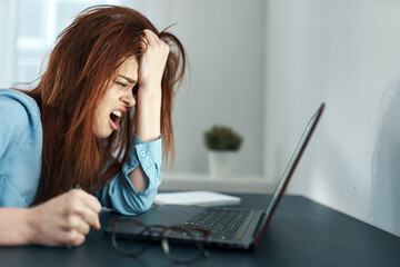 tired woman sitting at a table in front of a laptop work dissatisfaction