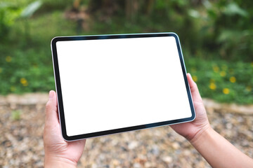Mockup image of a woman holding digital tablet with blank white desktop screen in the outdoors