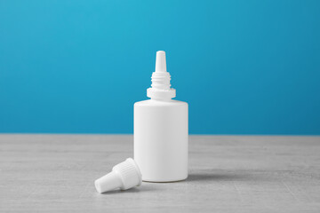 Nasal spray on white wooden table against light blue background